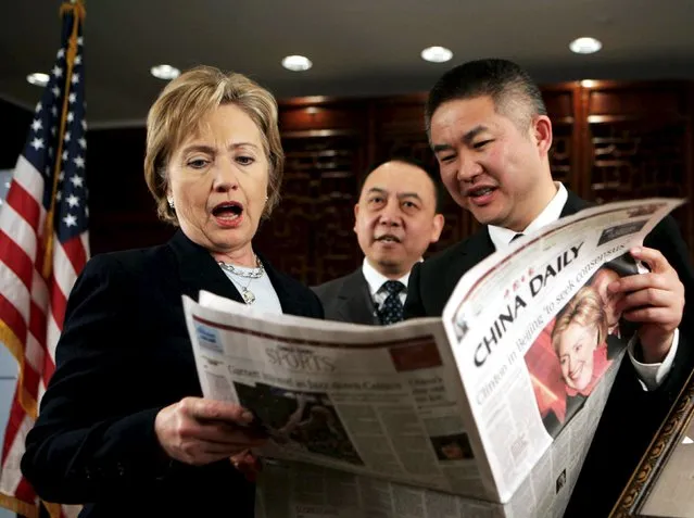 U.S. Secretary of State Hillary Clinton (L) reacts while reading a local English newspaper before conducting a web chat with Chinese internet users at the U.S. embassy in Beijing in this February 22, 2009 file photo. (Photo by Reuters/China Daily)