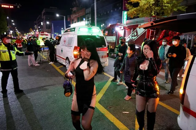 Partygoers walk by ambulances at the scene where dozens of people were injured in a stampede during a Halloween festival in Seoul, South Korea on October 29, 2022. Nearly 60 have died from a Halloween crush in Seoul, a fire department official said on October 30. (Photo by Kim Hong-ji/Reuters)