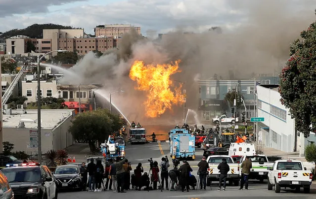 A Pacific Gas and Electric truck drives past a fire engine as San Francisco firefighters battle a fire on Geary Boulevard in San Francisco, Wednesday, February 6, 2019. A gas explosion in a San Francisco neighborhood shot flames high into the air Wednesday and was burning four buildings as utility crews scrambled to shut off the flow of gas. Construction workers cut a natural gas line, San Francisco Fire Chief Joanne Hayes-White said. (Photo by Stephen Lam/Reuters)