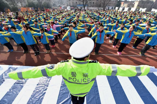 A policeman teaches traffic rules to primary school students at a school in Hefei, Anhui province, February 25, 2016. (Photo by Reuters/China Daily)