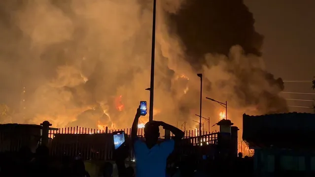 In this image made from video, residents watch a plume of smoke from a burning oil depot, in Conakry, Guinea, Monday, December 18, 2023. An explosion and inferno at Guinea’s main fuel depot in the capital of Conakry has left several people dead or injured. Guinea’s presidency says the fire broke out at the Guinean Petroleum Company depot shortly after a massive explosion past midnight Sunday. (Photo by AP Photo)