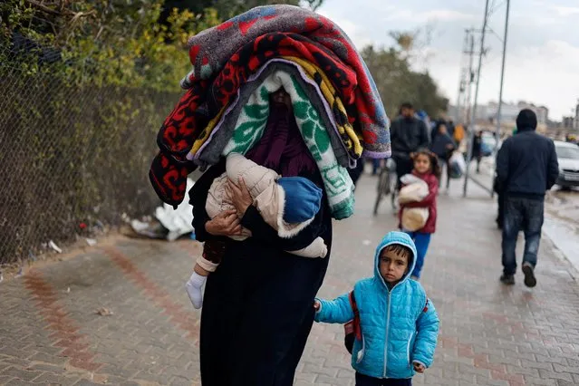 A woman holds a baby as Palestinians fleeing Khan Younis, due to the Israeli ground operation, move towards Rafah in the southern Gaza Strip on January 29, 2024. (Photo by Mohammed Salem/Reuters)