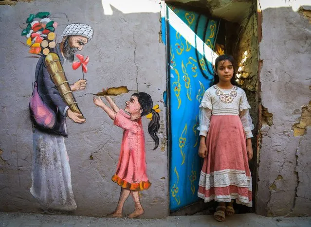 A colorful drawing is seen on a wall in Baghdad, Iraq on October 24, 2021. A group of volunteer painters tries to give hope and joy to the Iraqi residents by painting colorful murals on the walls of the houses and streets of the city, tired of violance. Seve-member group named “Butterfly Effect” is busy in drawing paintings to depict life in Baghdad and its cultural heritage on the buildings (Photo by Murtadha Al-Sudani/Anadolu Agency via Getty Images)