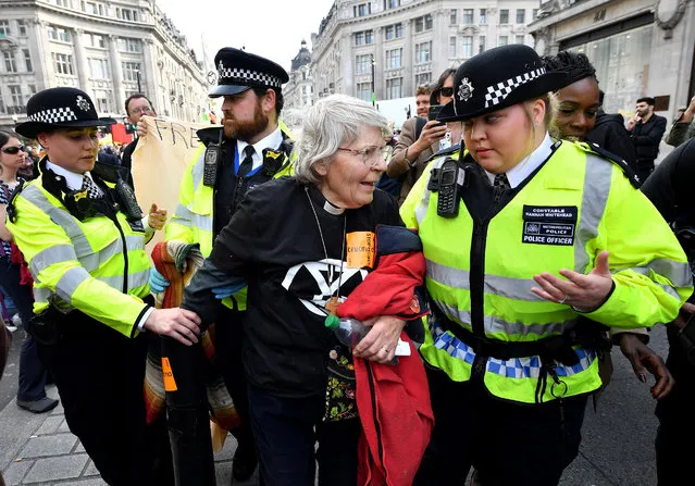 An Environmental campaigner wearing a clerical collar is removed by police officers at Oxford Circus during the fourth day of a coordinated protest by the Extinction Rebellion group on April 18, 2019 in London, England. More than 100 arrests have been made, with demonstrations blocking a number of locations across the capital. (Photo by Leon Neal/Getty Images)