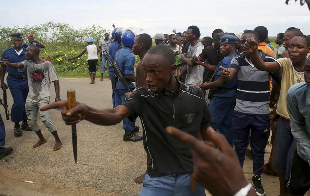 A mob gestures near a female police officer accused of shooting a protester in Buterere neighborhood of Bujumbura, Burundi, May 12, 2015. (Photo by Goran Tomasevic/Reuters)
