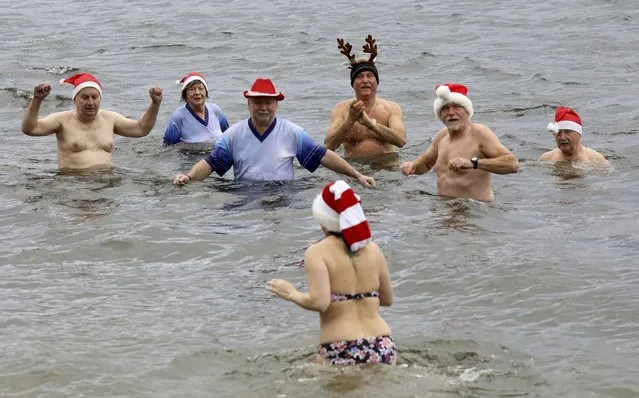 Members of the winter swimming club “Pirrlliepausen” go into Lake Senftenberg, which is four degrees cold (39 Farenheit) for their traditional Christmas swim, in Seftenberg, Germany, Friday, December 24, 2021.. Since 1987, the “Pirrlliepausen” have been going into the water twice a week in winter. “Pirrlliepausen” is an old North German expression for “icicles”. (Photo by Bernd W'stneck/dpa via AP Photo)