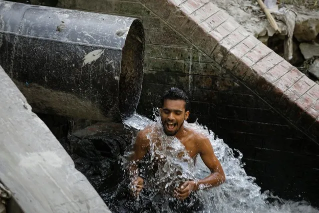 A man cools himself off as he stands under a municipality water pipe on a hot summer day in New Delhi, June 10, 2019. (Photo by Anuwar Hazarika/Reuters)