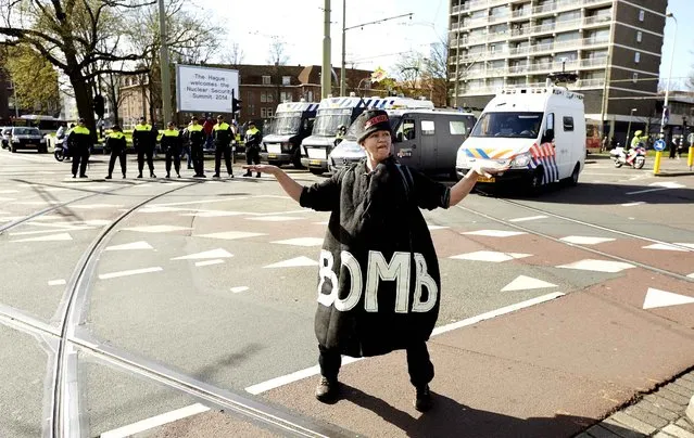 A womn wearing a coat reading “Bomb” stands in front of policemen during a protest by anti-nuclear activists under the slogan: “Stop nuclear power! Abolish Poverty!” on the eve of the Nuclear Security Summit in The Hague, The Netherlands, on March 23, 2014. World leaders are expected to pledge to beef up the fight against nuclear terror with the UN atomic watchdog playing a central role, a draft statement ahead of a two-day summit in The Hague showed. (Photo by Martijn Beekman/AFP Photo/ANP)