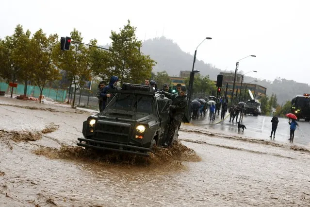A riot police vehicle crosses a flooded street in Santiago, April 17, 2016. (Photo by Ivan Alvarado/Reuters)
