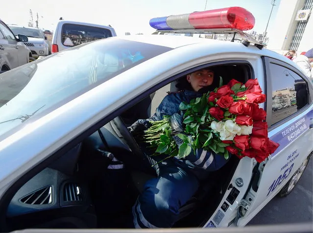 A traffic policeman gives flowers to female drivers ahead of International Women's Day in Vladivostok, Russia on March 7, 2017. (Photo by Yuri Smityuk/TASS via Getty Images)