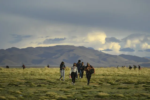 Migrants walks on the field after crossing into Chile from Bolivia, near Colchane, Chile, Thursday, December 9, 2021. (Photo by Matias Delacroix/AP Photo)