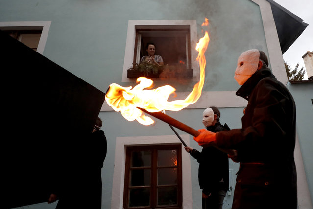 People watch from the window of their home as participants dressed in black, wearing masks, beating drums and pushing small carts making a synchronized and loud sound take part in an Easter procession marching through the streets of Ceske Budejovice, Czech Republic, Thursday, April 1, 2021. (AP Photo/Petr David Josek)
