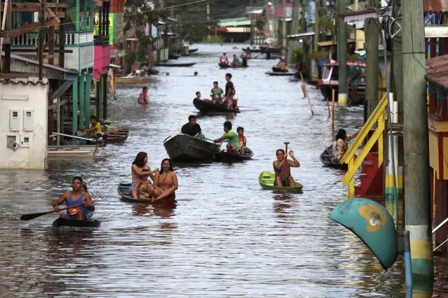Residents navigate a flooded street in Anama, Amazonas state, Brazil, Thursday, May 13, 2021. (Photo by Edmar Barros/AP Photo)