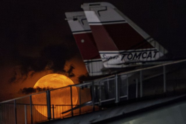 The flower moon sets behind Grumman F-14 Tomcat fighter jets at the Intrepid Museum, Thursday, May 23, 2024, in New York. (Photo by Julia Nikhinson/AP Photo)