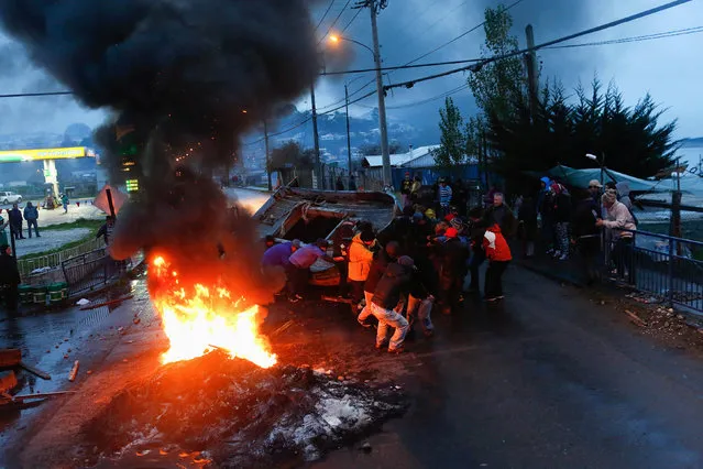 Fishermen block a road with a boat during a protest calling on the government to help ease the economic effects of an harmful algal bloom that had affected their livelihoods, at Ancud on Chiloe island in Chile, May 5, 2016. (Photo by Pablo Sanhueza/Reuters)