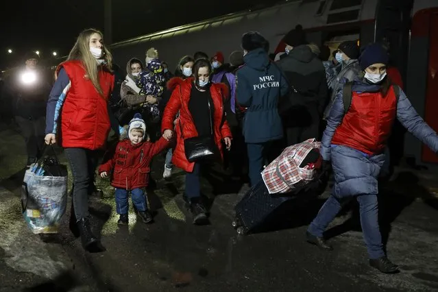 People from the Donetsk and Luhansk regions, the territory controlled by a pro-Russia separatist governments in eastern Ukraine, walk from a train to be taken to temporary residences in the Volgograd region, at the railway station in Volzhsky, Volgograd region, Russia, on Sunday, February 20, 2022. Ukrainian President Volodymyr Zelenskyy, facing a sharp spike in violence in and around territory held by Russia-backed rebels and increasingly dire warnings that Russia plans to invade, has called for Russian President Vladimir Putin to meet him and seek a resolution to the crisis. (Photo by Alexandr Kulikov/AP Photo)