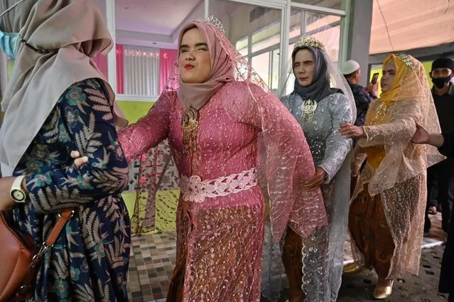 Visually-impaired brides lead each other as they enter a wedding hall during a mass marriage for ten couples with the disability on the “22-2-22” palindrome day in Bogor on February 22, 2022. (Photo by Adek Berry/AFP Photo)