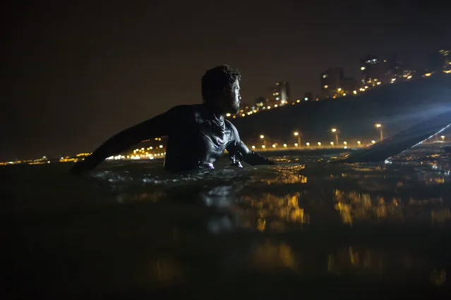 In this March 8, 2017 photo, Ernesto Benavides waits to catch a wave in La Pampilla beach in Lima, Peru. Night surfing came about in Lima because of a dispute with the capital municipality that in 2015 increased the width of a road that goes by the coast. (Photo by Rodrigo Abd/AP Photo)