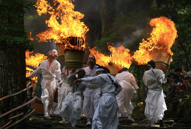 White-robed men hold up flaming torches during an annual fire festival at the World Heritage-listed Kumano Nachi Taisha shrine in the Wakayama Prefecture town of Nachikatsuura, western Japan, on July 14, 2024. (Photo by Kyodo News)