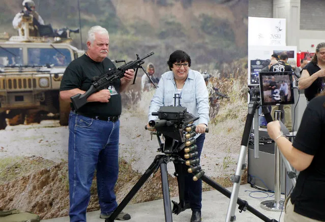 Gun enthusiasts poses for a picture with an FN MK 48 machine gun and a MK 19 grenade launcher at the National Rifle Association's annual meetings & exhibits show in Louisville, Kentucky, May 21, 2016. (Photo by John Sommers II/Reuters)