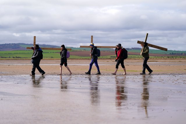 Pilgrims celebrate Easter by carrying wooden crosses as they walk over the tidal causeway to Lindisfarne during the final leg of their annual Good Friday pilgrimage on April 7, 2023 in Berwick-upon-Tweed, England. Pilgrims annually celebrate Easter by crossing at low tide to Lindisfarne, a trek that follows a walk of between 70 to 120 miles in the days leading up to Good Friday. Lindisfarne has become known as Holy Island because of the part it played in the story of bringing the Christian gospel to England. In the 7th Century, King Oswald of Northumbria granted Lindisfarne to Aidan, a monk and missionary, so that he could establish a monastery modelled on one in which he lived on the island of Iona. (Photo by Ian Forsyth/Getty Images)