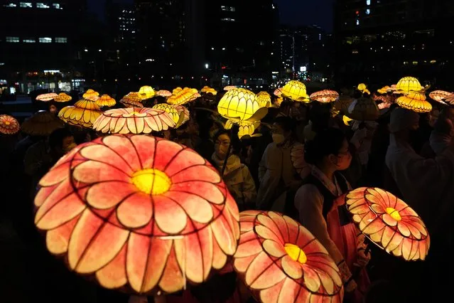 South Korean Buddhists wearing face masks, carry colorful lotus lanterns during the lighting ceremony to celebrate for the upcoming birthday of Buddha on May 8, in Seoul, South Korea, Tuesday, April 5, 2022. (Photo by Lee Jin-man/AP Photo)