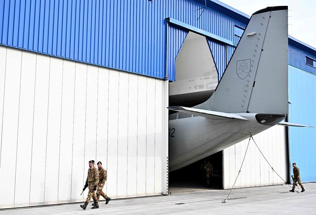 The tail of a Slovak military plane is seen at a hangar as Italian soldiers walk past after a visit of Slovakia's President and her Italian counterpart at Kuchyna Air Base, north of Bratislava, on April 19, 2023. The US Patriot air defence system is replacing the Italian SAMP/T Mamba tactical system in the premises of the Kuchyna Air Base. The systems have been operated by up to 150 members of the armed forces of Italy. (Photo by Joe Klamar/AFP Photo)