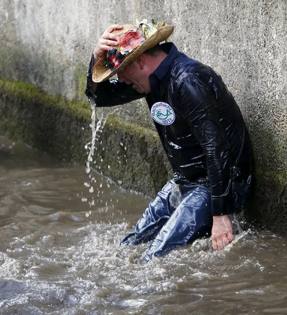 A fisherman takes a break after catching trouts in a small river during the Fischertag (Fisherman's Day) in downtown Memmingen, southern Germany, July 25, 2015. (Photo by Michaela Rehle/Reuters)