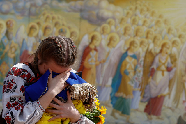 Ivanna Sanina reacts as she holds a Ukrainian national flag and a portrait of her boyfriend Christopher Campbell, U.S. military volunteer of the International Legion for the Defense of Ukraine, who was killed in a fight against Russian troops in the frontline town of Bakhmut, amid Russia's attack on Ukraine, during his funeral in Kyiv, Ukraine on May 5, 2023. (Photo by Valentyn Ogirenko/Reuters)