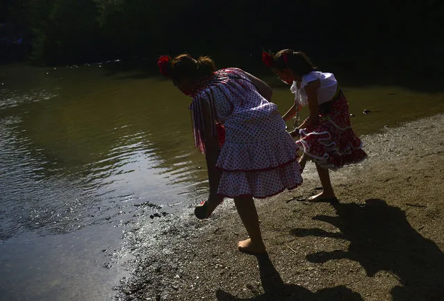 Pilgrims in traditional costume removes their shows before crossing the Quema river during the annual El Rocio pilgrimage in Villamanrique, near Sevilla on June 1, 2017. (Photo by Cristina Quicler/AFP Photo)