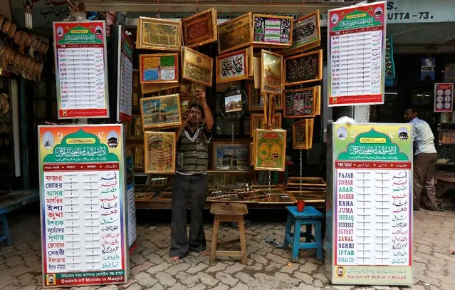 A salesman hangs religious pictures for sale ahead of the Muslim fasting month of Ramadan in Kolkata, India, June 6, 2016. (Photo by Rupak De Chowdhuri/Reuters)