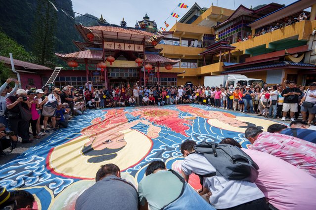 Devotees unveil a giant canvas of sacred “Thangka” measuring 60 meters (197 feet) by 12 meters (39 feet), under the sun during a Wesak day celebration in Ipoh, Malaysia, Wednesday, May 22, 2024. Wesak Day, one of the holiest days for Buddhists, offers an opportunity for all followers to come together and celebrate not only Buddha's birthday, but also his enlightenment and achievement of nirvana. (Photo by Vincent Thian/AP Photo)