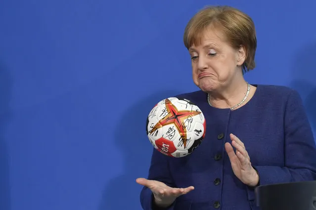 German Chancellor Angela Merkel plays with a handball given to her by the German Handball Federation's president (not in picture) as she received the German national handball team at the Chancellery in Berlin on April 8, 2019. (Photo by John Macdougall/AFP Photo)
