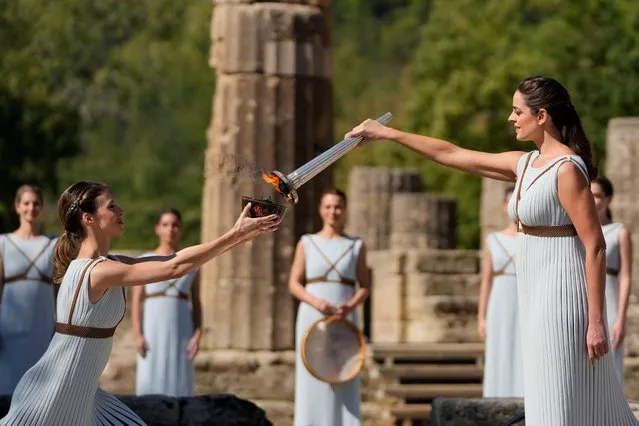 Greek actress Xanthi Georgiou, playing the role of the High Priestess, lights the torch during the flame lighting ceremony for the Beijing 2022 Winter Olympics at the Ancient Olympia archeological site, birthplace of the ancient Olympics in southern Greece on October 18, 2021. The Olympic flame will once again be lit in an empty stadium on October 18, 2021, as it starts its truncated journey to Beijing for the Winter Games in February. Like the ceremony in March 2020 to light the flame for Tokyo, and like those Games, which were put back a year, Monday's ceremony is a victim of coronavirus restrictions. (Photo by Thanassis Stavrakis/Reuters)