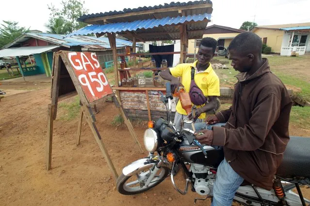 A man sells black market gasoline products on a road side in Paynesville, outside Monrovia, Liberia, 06 June 2022. Liberia is experiencing a shortage of gasoline products, which is being sold for the equivalent of 6.33 US dollar per gallon. The shortage is believed to be caused by the Russia-Ukraine conflict, as global supply chains have been interrupted due to the conflict. (Photo by Ahmed Jallanzo/EPA/EFE)