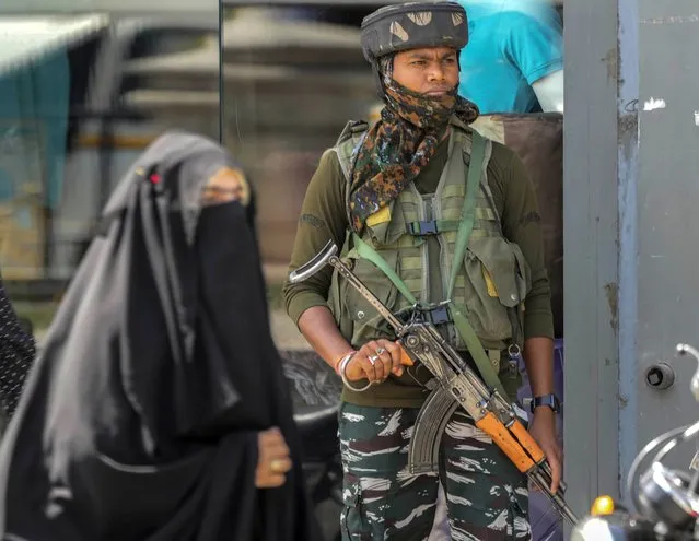 An Indian paramilitary soldier guards as a Muslim woman walks at a market in Srinagar, Indian controlled Kashmir, Thursday, June 2, 2022. (Photo by Mukhtar Khan/AP Photo)