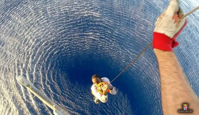 A migrant is rescued by an Italian Navy helicopter in the area where his boat sank in the Mediterranean Sea in this August 11, 2015 handout courtesy of the Italian Navy. Up to 50 migrants went missing after a large rubber dinghy sank in the Mediterranean Sea, Italian rescuers said on Wednesday, while more than 1,500 were picked up from other vessels in the past 24 hours. (Photo by Reuters/Italian Navy)