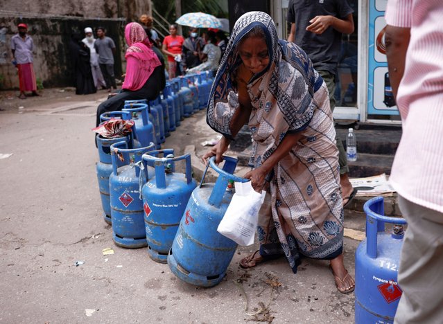 A woman moves a gas tank as she stands in line to buy another tank near a distributor, amid the country's economic crisis, in Colombo, Sri Lanka, June 1, 2022. (Photo by Dinuka Liyanawatte/Reuters)