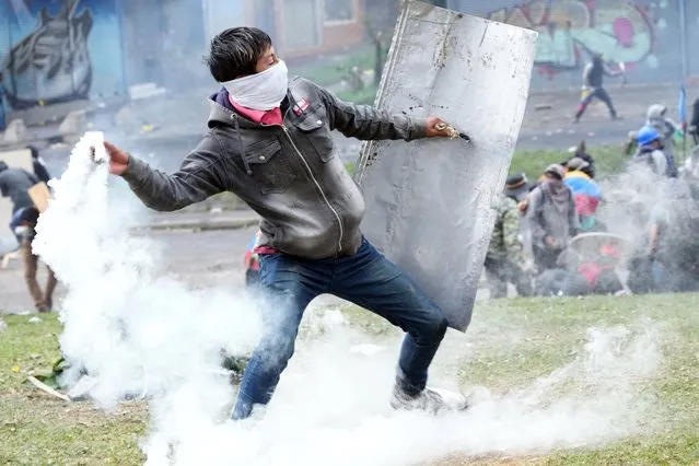 A protester returns a tear gas canister during clashes with police in downtown Quito, Ecuador, Friday, June 24, 2022. The protesters are part of a national strike that the Confederation of Indigenous Nationalities began June 14 to demand that gasoline prices be cut, price controls for agricultural products and a larger budget for education. (Photo by Dolores Ochoa/AP Photo)