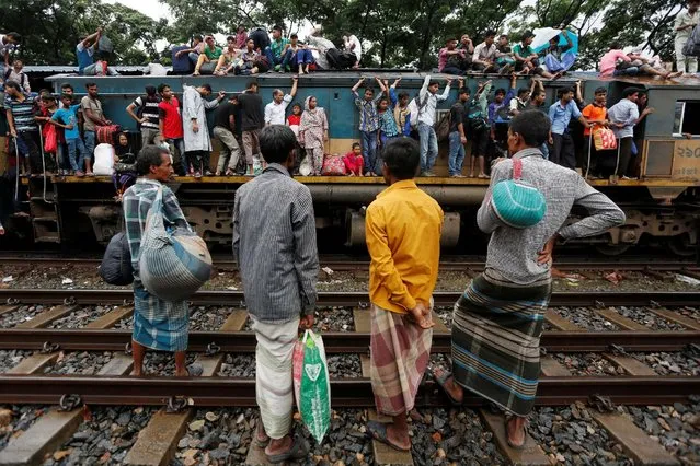 People sit atop and stand outside on an engine of an overcrowded passenger train as they travel home to celebrate Eid al-Fitr festival, which marks the end of the Muslim holy fasting month of Ramadan, at a railway station in Dhaka, Bangladesh, July 5, 2016. (Photo by Adnan Abidi/Reuters)