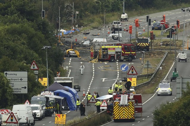 Emergency services and crash investigation officers work at the site where a Hawker Hunter fighter jet crashed onto the A27 road at Shoreham near Brighton, Britain August 23, 2015. A jet aircraft ploughed into several cars on a busy road near an airshow in southern England on Saturday, killing at least seven people, police said. (Photo by Luke MacGregor/Reuters)