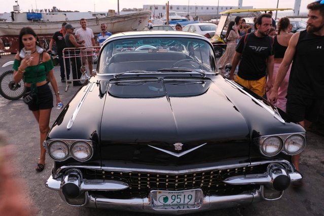 People look at a 1958 Cadillac Fleetwood during a classic and luxury car parade at the fishermen's port of the northern Lebanese city of Batroun, on August 6, 2022. (Photo by Ibrahim Chalhoub/AFP Photo)