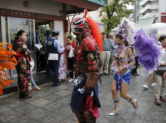 A woman (L) clad in a kimono looks at dancers after they perform during the 34th annual Asakusa Samba Carnival in Tokyo August 29, 2015. (Photo by Toru Hanai/Reuters)