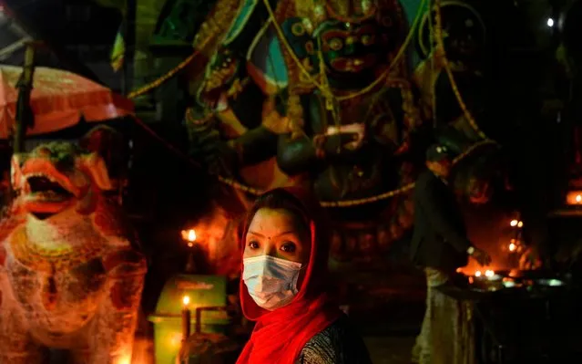 A Hindu woman wears a facemask as a preventive measure against the COVID-19 coronavirus while visiting Durbar Square to workship in Kathmandu on March 19, 2020. (Photo by Prakash Mathema/AFP Photo)