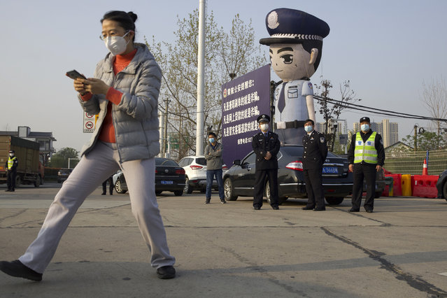 Police officers wearing face masks to protect against the spread of new coronavirus stand near a toll gate for vehicles entering and exiting Wuhan in central China's Hubei Province, Wednesday, April 8, 2020. (Photo by Ng Han Guan/AP Photo)