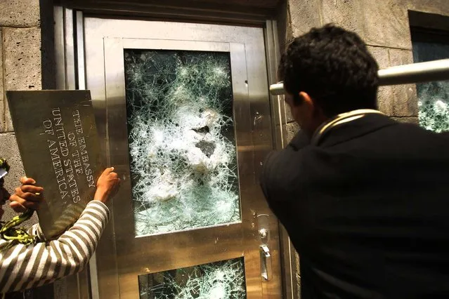 Inside the grounds of the embassy in Sanaa, protesters break the windows of a door. (Photo by Hani Mohammed/Associated Press)