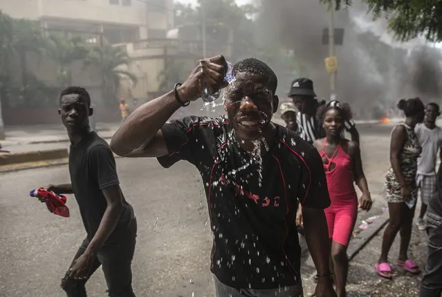 A protester affected by tear gas fired by police splashes water on his face, during a protest to demand that Haitian Prime Minister Ariel Henry step down and call for a better quality of life, in Port-au-Prince, Haiti, Monday, August 29, 2022. (Photo by Odelyn Joseph/AP Photo)