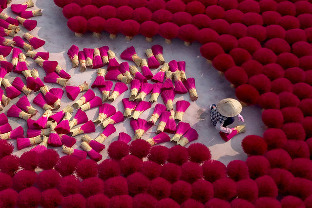 This aerial picture shows a worker arranging dried incense sticks to dry in a courtyard in Quang Phu Cau village on the outskirts of Hanoi on January 21, 2025, ahead of Lunar New Year celebrations, known in Vietnam as Tet. (Photo by Nhac Nguyen/AFP Photo)