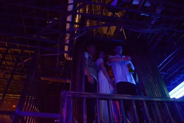 This picture taken on September 9, 2014 shows a waiter (R) and a group of people using an elevator at a prison themed restaurant in Tianjin. (Photo by Wang Zhao/AFP Photo)