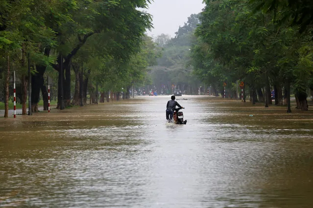 A man pushes his motorcycle along flooded road after typhoon Damrey hits Vietnam in Hue city on November 5, 2017. (Photo by Reuters/Kham)